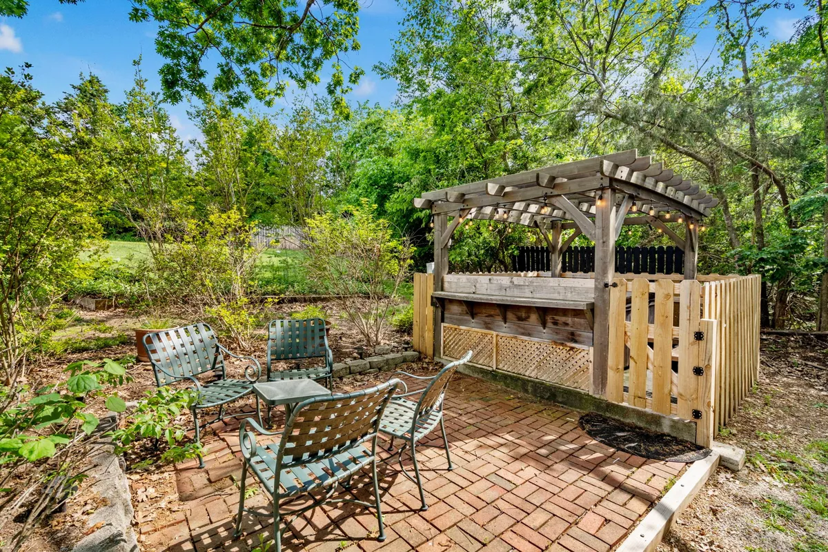 This scene shows an outdoor bar area with comfortable seating surrounded by greenery. String lights hint at lively gatherings during sunset or nighttime, while the seating invites group dining or friendly conversations outdoors. The setup is ideal for barbecues, picnics, and sunset celebrations.