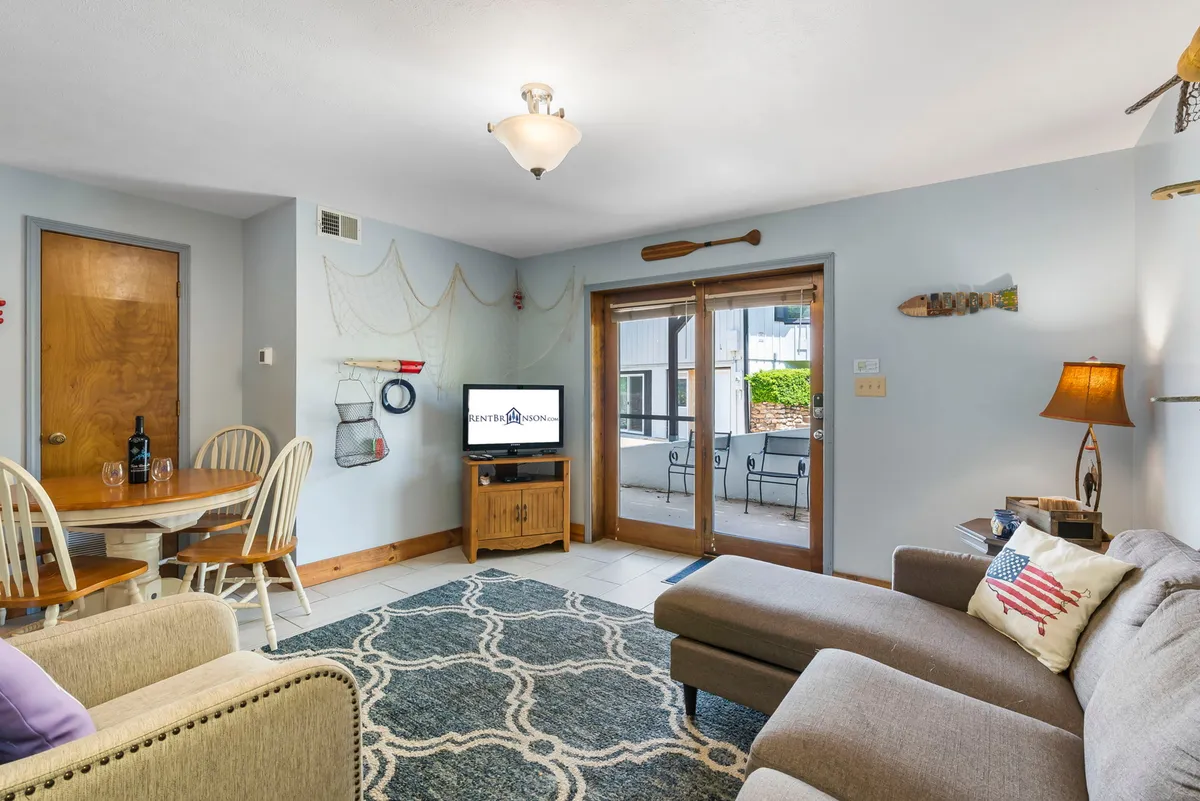 A stylish interior featuring a cozy seating area, dining table, and decorative wall elements. The arrangement is ideal for socializing, watching TV, or sharing a meal, echoing the suite's spirit of comfort and togetherness.