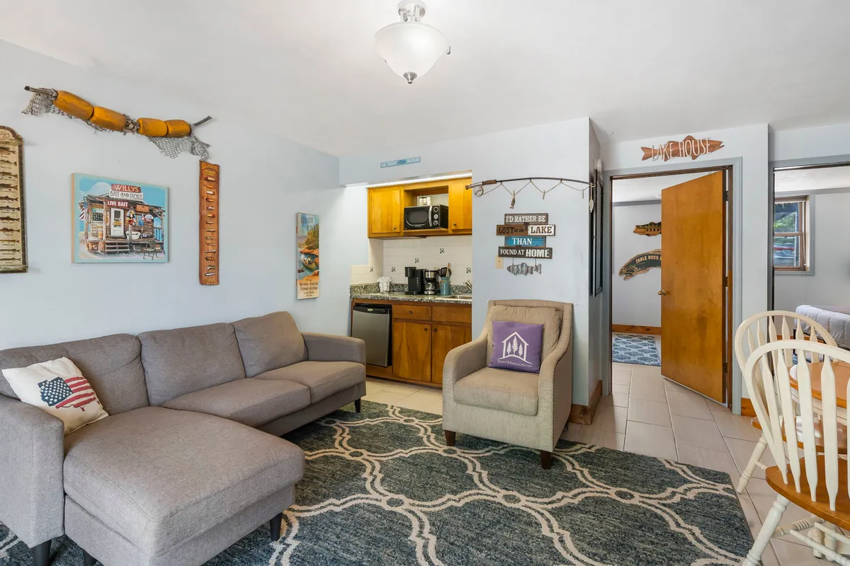 A spacious interior with a sofa, dining table, and kitchen area, accented by decorative wall art. The space is designed for relaxation, socializing, cooking, and dining, exuding a cozy and inviting atmosphere.