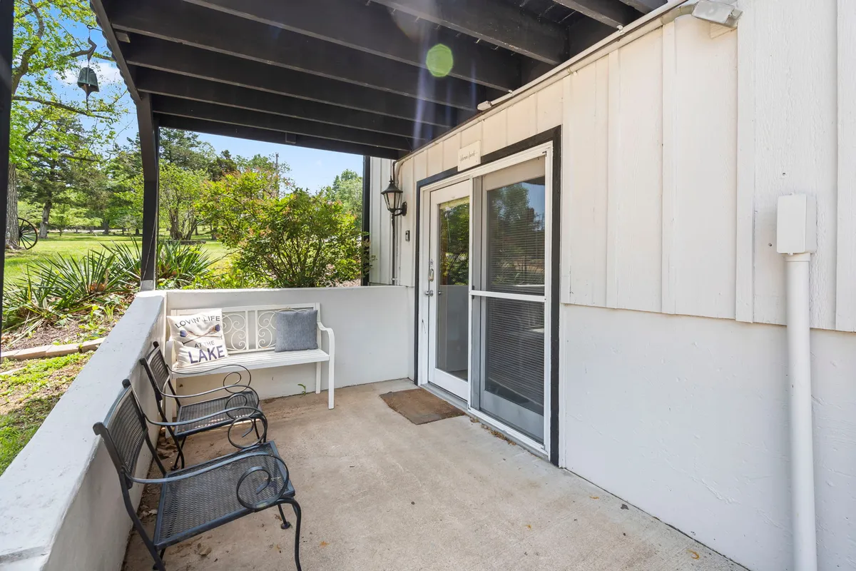 This image showcases the front porch of the property, complete with benches and surrounding greenery. The scene is welcoming and peaceful, suggesting a perfect spot for relaxing outdoors with a pet or enjoying a morning coffee while overlooking nature.